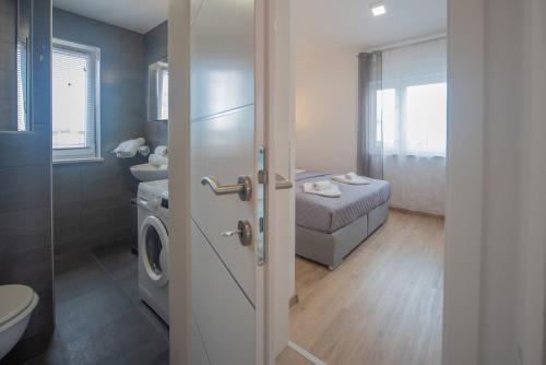 a bathroom with a washing machine and a bathroom with a bed at Apartments LAURA in Fažana