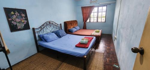 a small bedroom with a bed and a chair at Tatai Kumang Homestay in Kuching