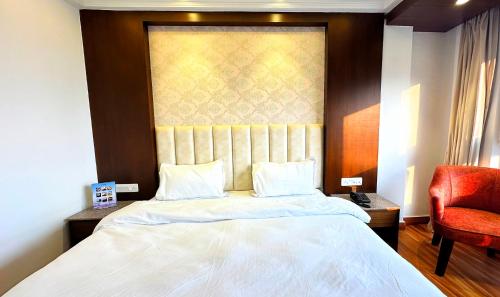 a bedroom with a large bed and a red chair at Sangam by Stotrak, Jhula Ghar Mussoorie in Mussoorie
