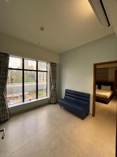 a living room with a blue couch and a window at The Hub Link in Mumbai