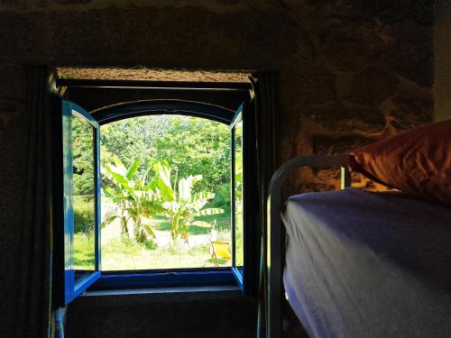 ein Fenster in einem Zimmer mit Blick auf ein Bett in der Unterkunft Quinta Estrada Romana - Albergue de Peregrinos in Cerdal