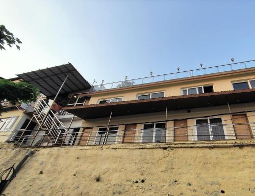 a building with a staircase in front of it at Sangam by Stotrak, Jhula Ghar Mussoorie in Mussoorie