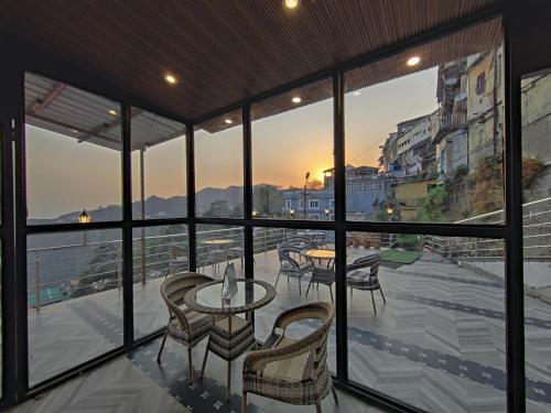 a balcony with tables and chairs and a view of a city at Sangam by Stotrak, Jhula Ghar Mussoorie in Mussoorie
