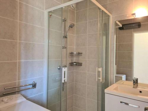 une douche avec une porte vitrée à côté d'un lavabo dans l'établissement La Rouquille Cap d'Agde,, au Cap d'Agde