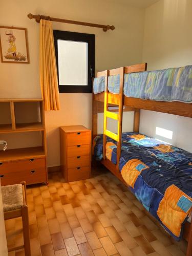 une chambre avec deux lits superposés et une commode dans l'établissement La Rouquille Cap d'Agde,, au Cap d'Agde