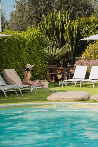 a woman sitting on a chair next to a swimming pool at MelRose Relais in Massa Lubrense