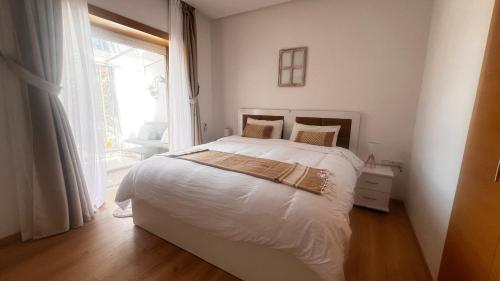 Habitación blanca con cama y ventana en Prestigia,Golf, piscine, soleil, paysage, sport, spacieux,lux résidence, en Marrakech