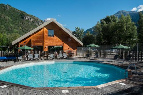 una gran piscina frente a una cabaña de madera en Huttopia Vallouise en Vallouise