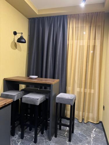a dining table and stools in a room with a curtain at Apartments Lux in city center Lviv in Lviv