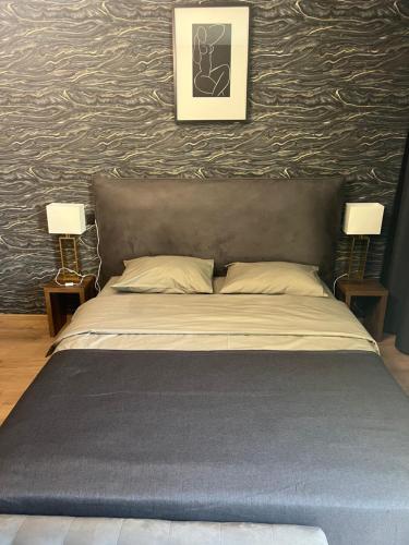 a bed in a bedroom with two lamps and a wall at Apartments Lux in city center Lviv in Lviv