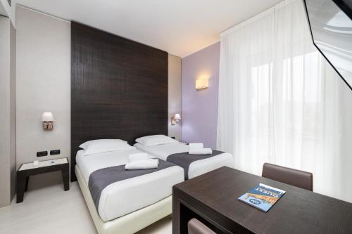 a hotel room with two beds and a table and a desk at Hotel Maggiore in Bologna