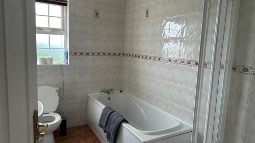 a white bathroom with a tub and a toilet at Four bedroomed Townhouse in Letterkenny