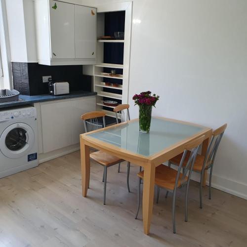 a dining room table with chairs and a vase of flowers on it at Alastrean Flat in Aberdeen