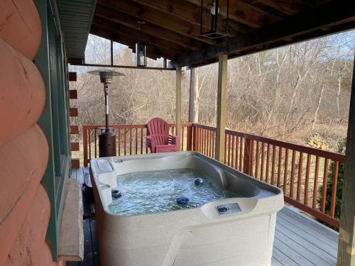 a hot tub on a deck with a chair at The Cabin in Hammondsport
