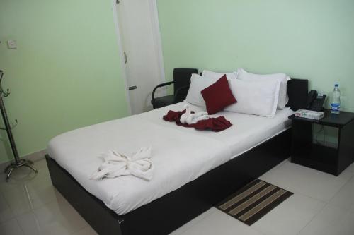 a bed with white sheets and red pillows on it at Grand Selim Resort & Tour – GSRT in Sreemangal
