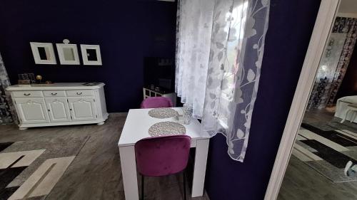 Cette chambre comprend une table blanche et des chaises violettes. dans l'établissement Studio apartman Marta, à Korenica