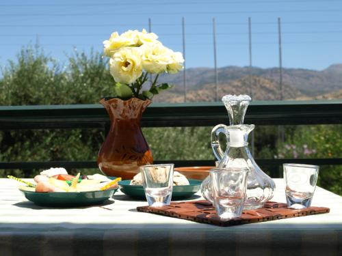 a table with a vase and glasses on a table with flowers at Kastro Studios Apartments in Myrtos