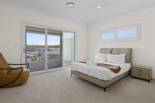 Dormitorio blanco con cama y ventana grande en Seaside Bliss with Ocean Views, en Catherine Hill Bay