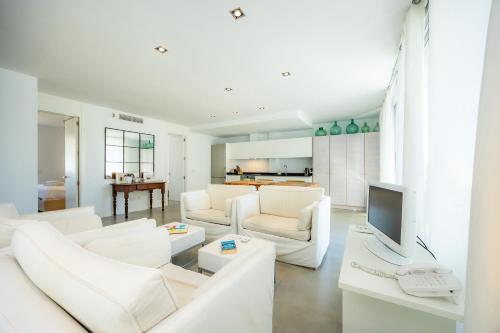 a living room with white furniture and a television at Can Fiol ii in Port de Pollensa