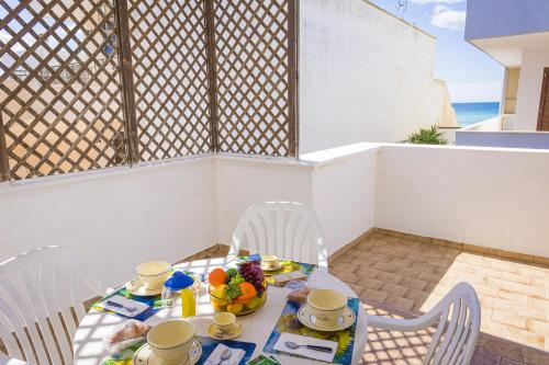 una mesa con sillas y una mesa con comida. en Torre Lapillo Apartment Sea View - Happy Rentals, en Porto Cesareo