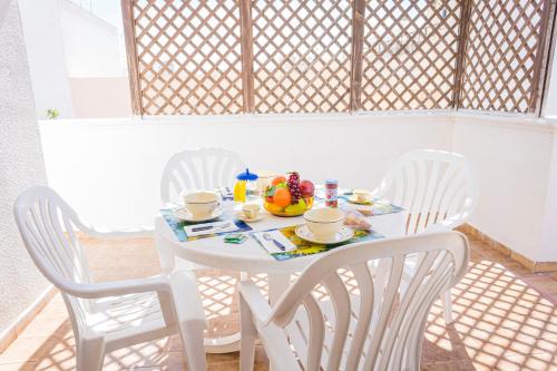 una mesa blanca con sillas blancas y un bol de fruta en ella en Torre Lapillo Apartment Sea View - Happy Rentals, en Porto Cesareo