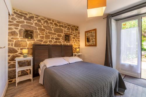 um quarto com uma cama e uma parede de pedra em Gîtes Ker Mané em Erdeven