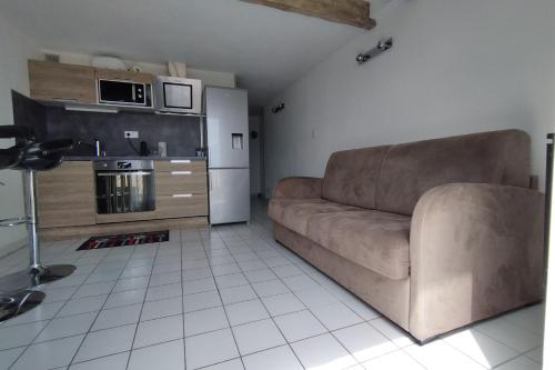 un salon avec un canapé marron et une cuisine dans l'établissement T2 with swimming pool and sea accessair cooled, à Frontignan