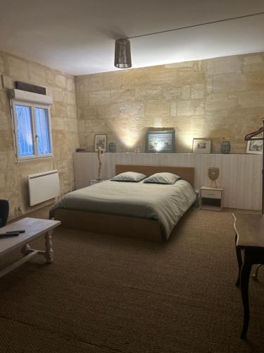 a bedroom with a bed and a stone wall at La Beycheliere in Saint-Julien-Beychevelle