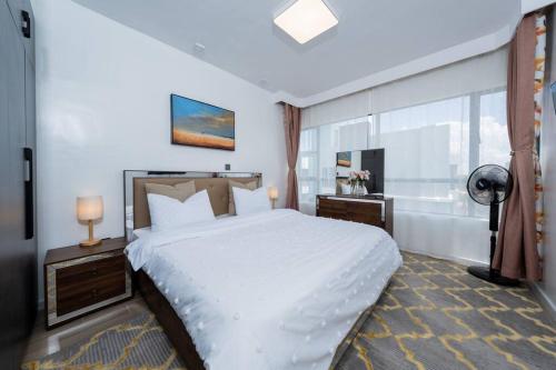 a bedroom with a large white bed and a window at InDesign 3BR Suite near JKIA SGR w Gym and Pool in Nairobi