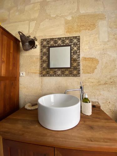 a bathroom with a large white sink on a wooden counter at La Beycheliere in Saint-Julien-Beychevelle