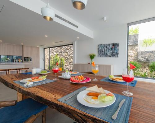 eine Küche mit einem Holztisch, auf dem Speisen und Weingläser stehen in der Unterkunft Ocean Front Villa Nha Trang in Nha Trang