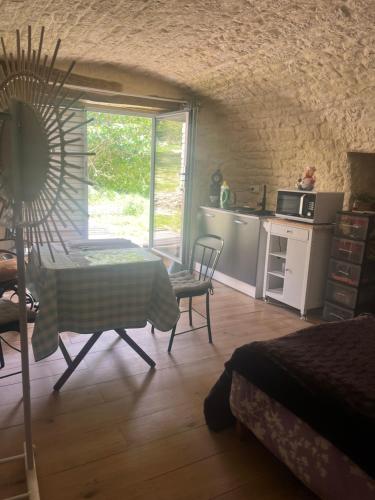 une chambre avec une table et une cuisine avec une fenêtre dans l'établissement Voute des anges type loft sans cloison, à Castelnau-de-Montratier