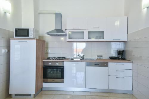 a kitchen with white cabinets and a stove top oven at Sandrina Residences in Vrsi