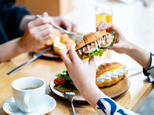 two people sitting at a table eating a sandwich at Kaname Inn Tatemachi in Kanazawa