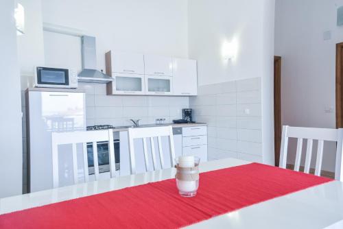 a kitchen with a table with a red rug at Sandrina Residences in Vrsi