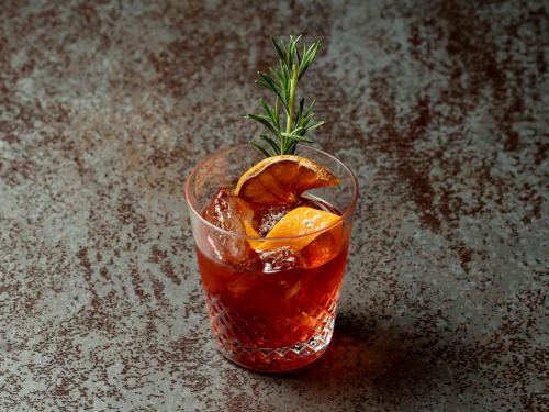 a drink with an orange peel and a rosemary garnishment at Kaname Inn Tatemachi in Kanazawa