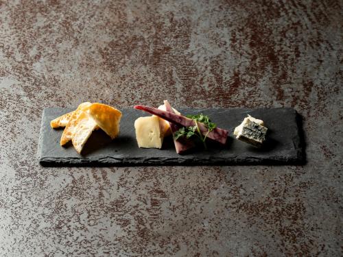 a black plate with different types of cheese on it at Kaname Inn Tatemachi in Kanazawa