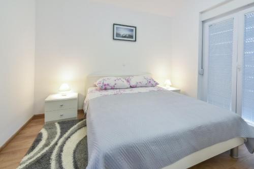a white bedroom with a bed and two night stands at Sandrina Residences in Vrsi