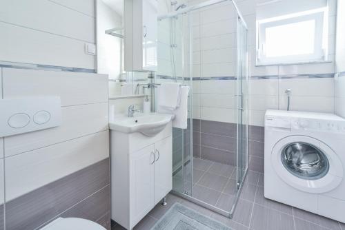 a white bathroom with a sink and a washing machine at Sandrina Residences in Vrsi