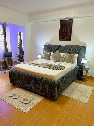 a large bed in a bedroom with slippers on the floor at Luxurious Homely Apt 6 in Kisumu