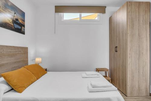 a white bedroom with a bed and a wooden cabinet at Casa Sol de Conil in Conil de la Frontera