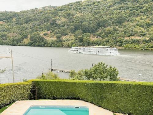 a boat on a river with a cruise ship in the water at Casa da Recosta Douro Country House in Resende