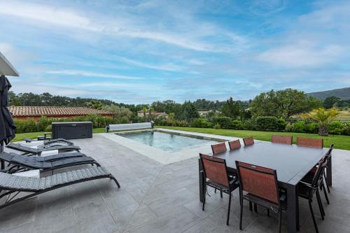 un patio avec une table et des chaises et une piscine dans l'établissement La Villa Danaud - Maison avec piscine et jacuzzi, à Vailhauquès