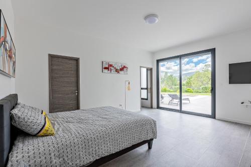 une chambre avec un lit et une porte coulissante en verre dans l'établissement La Villa Danaud - Maison avec piscine et jacuzzi, à Vailhauquès