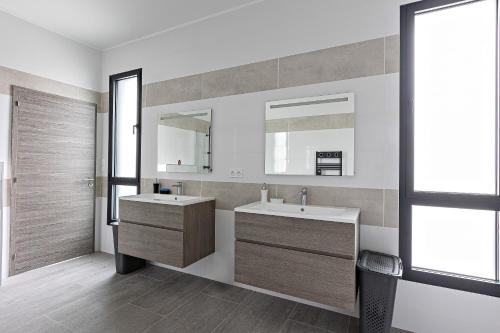une salle de bain avec deux lavabos et un miroir dans l'établissement La Villa Danaud - Maison avec piscine et jacuzzi, à Vailhauquès