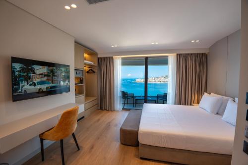 a hotel room with a bed and a desk and a window at Hotel Teuta in Sarandë