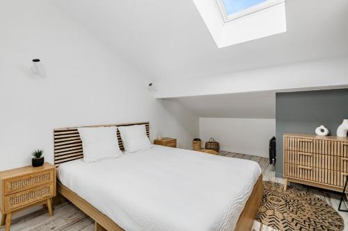 une chambre avec un lit blanc et une lucarne dans l'établissement COCON - Appartement neuf et confort, à Saint-Étienne