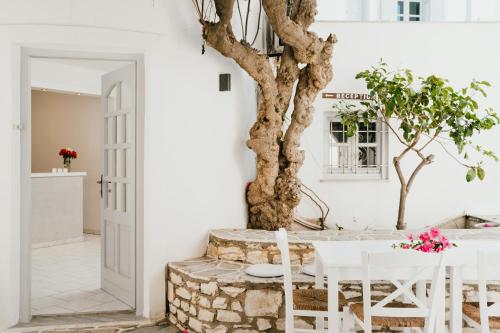 a white dining room with a table and a tree at Sunrise Paros in Naousa