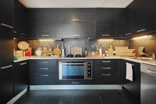 a kitchen with black cabinets and a microwave at Unique Villa Near Lisbon with Pool & Magical Decor in Cheira Ventos