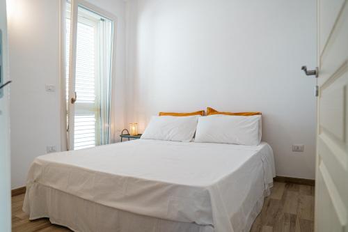 a white bed in a white bedroom with a window at La Casa al mare Torre San Giovanni in Torre San Giovanni Ugento